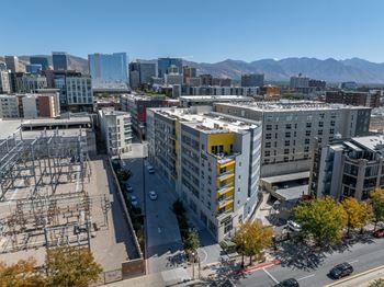 A cityscape with a large building in the foreground and mountains in the background.